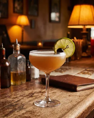 Tequila Sour in a coupe with lime and a cocktail cherry