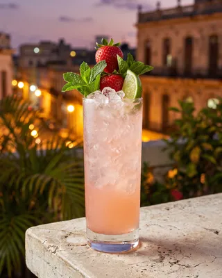 Strawberry Mojito in a Collins glass with strawberry, mint and lime