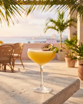Passion Fruit Daiquiri in a daiquiri glass with passion fruit and lime