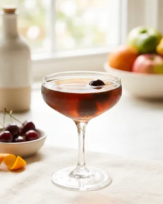 Black Manhattan in a coupe with a cocktail cherry