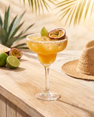 Passion Fruit Margarita in a margarita glass with lime and passion fruit