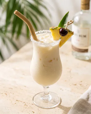 Non-alcoholic Piña Colada in a hurricane glass with pineapple and a cocktail cherry