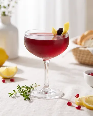 Pink & Bubbly Cocktail in a coupe with lemon and a cocktail cherry
