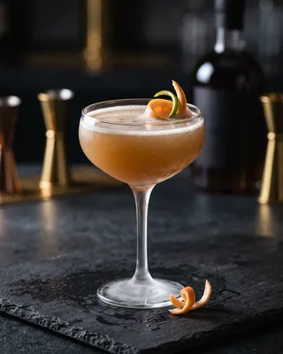 Undead Gentleman in a frosted coupe on dark slate, grapefruit and lime twists resting in the drink