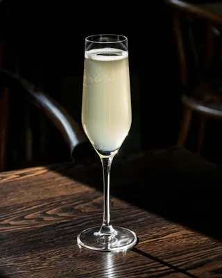 Death in the Afternoon in a Champagne flute on a wooden bar table