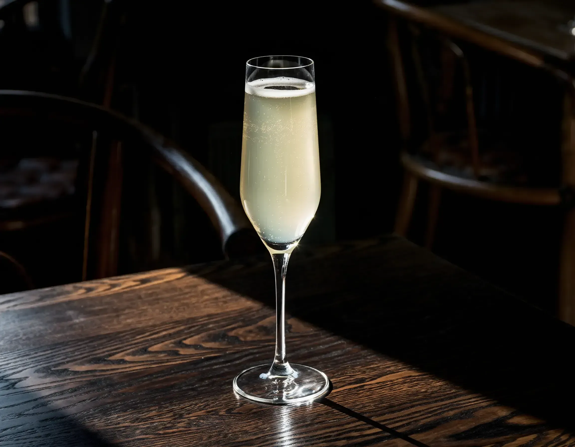 Death in the Afternoon in a Champagne flute on a wooden bar table